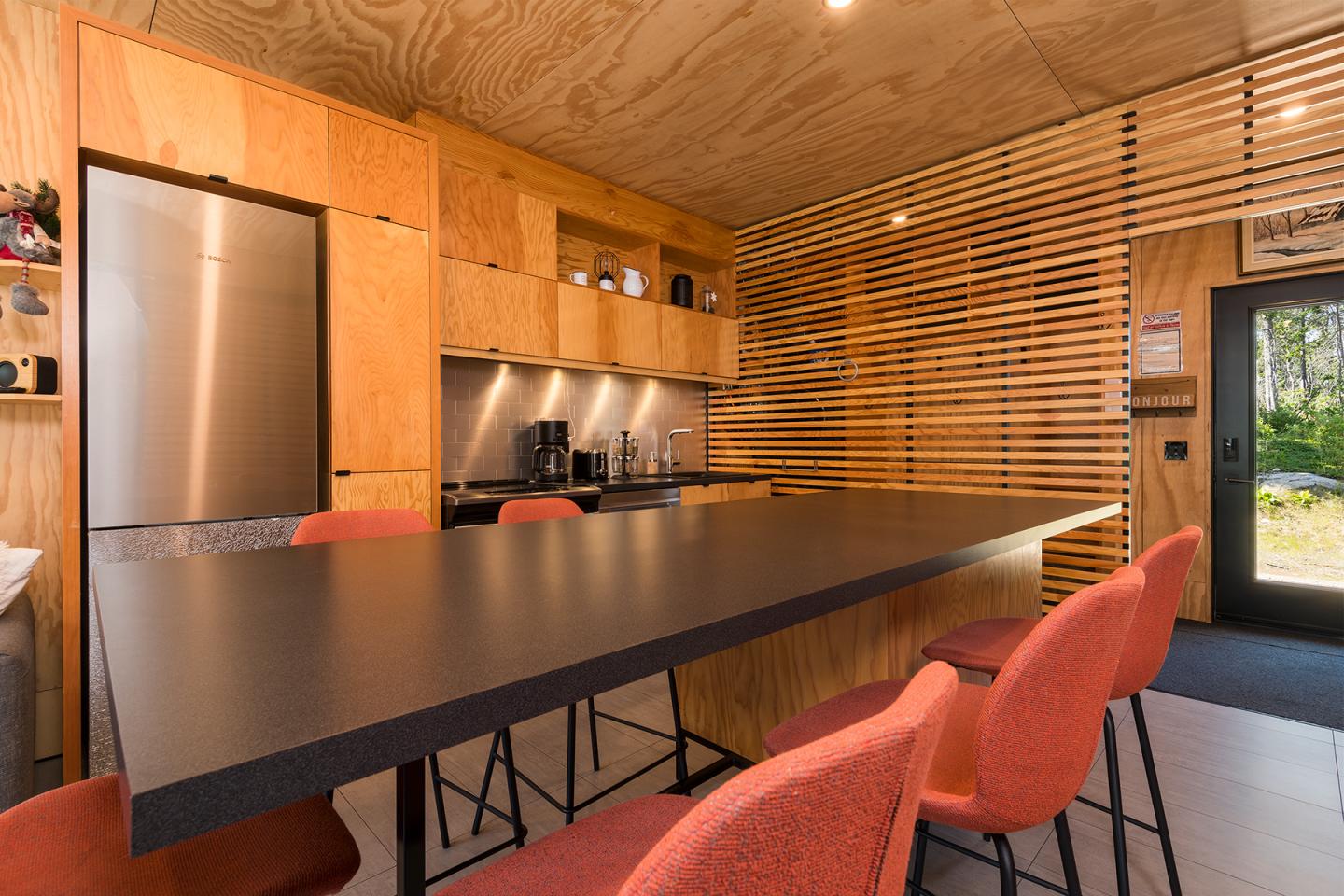 Cuisine moderne en bois avec grand îlot et chaises orange.