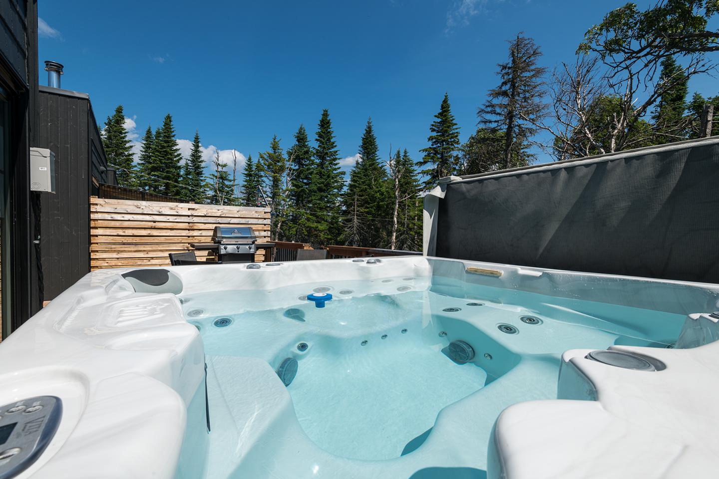 Spa extérieur avec vue sur des arbres et un ciel bleu.