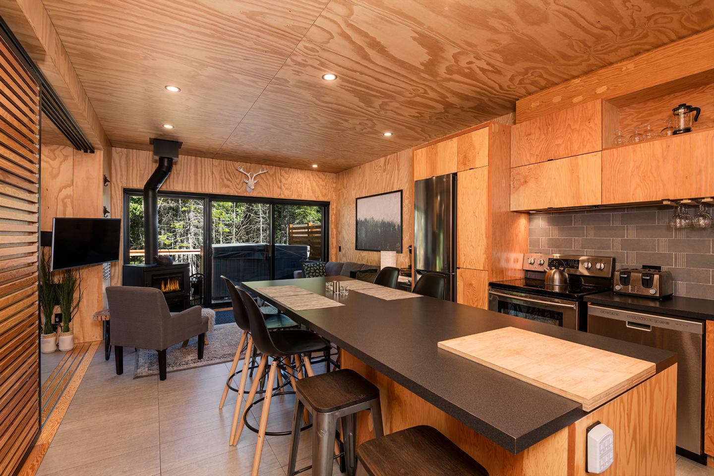Cuisine moderne en bois avec îlot central et vue sur terrasse vitrée.