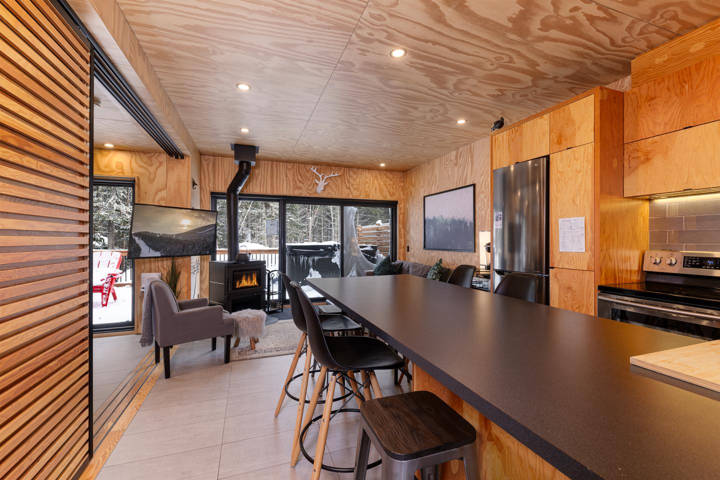 Intérieur de cuisine moderne en bois, avec table longue et cheminée.