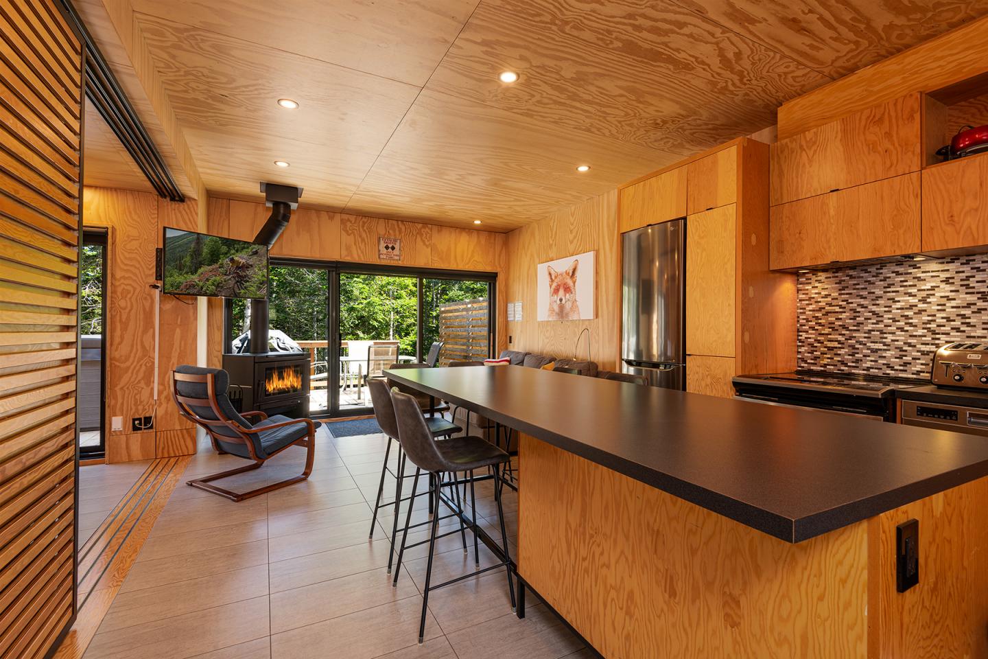 Cuisine moderne avec un comptoir noir, bois clair, et vues sur jardin.