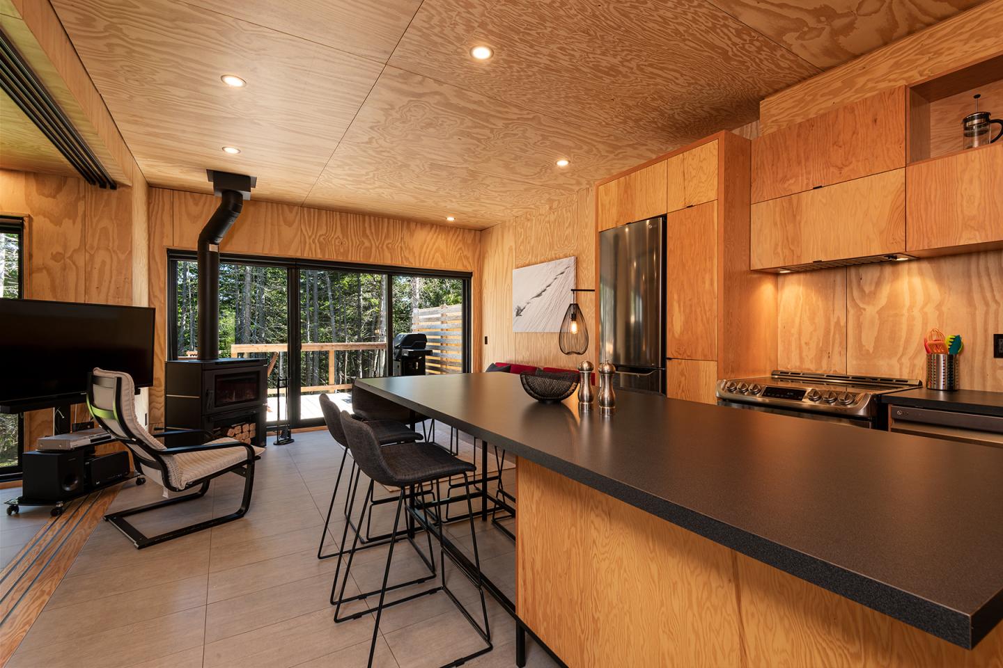 Cuisine moderne en bois clair avec un îlot central et grandes baies vitrées.