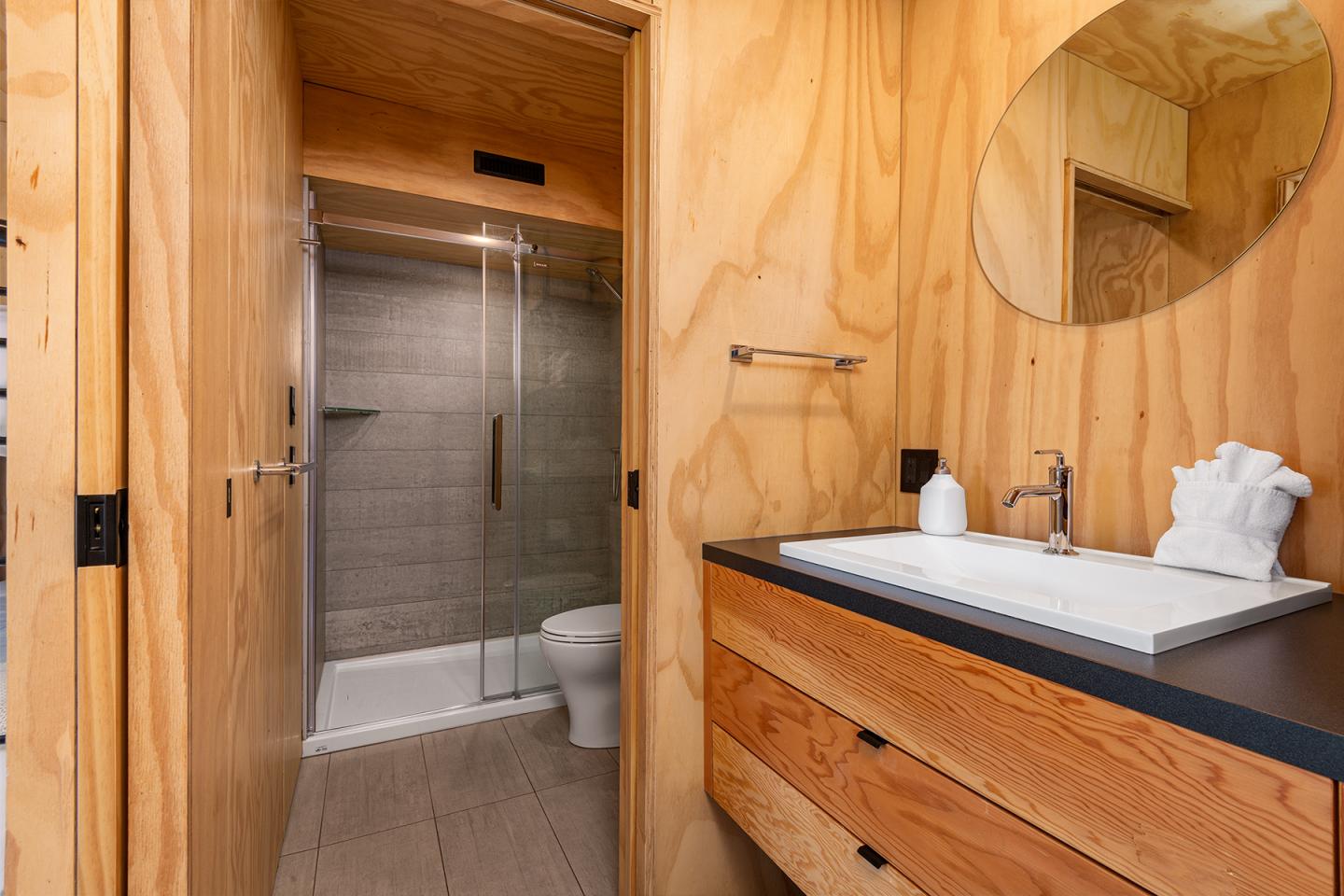 Salle de bain moderne en bois avec lavabo et douche vitrée.