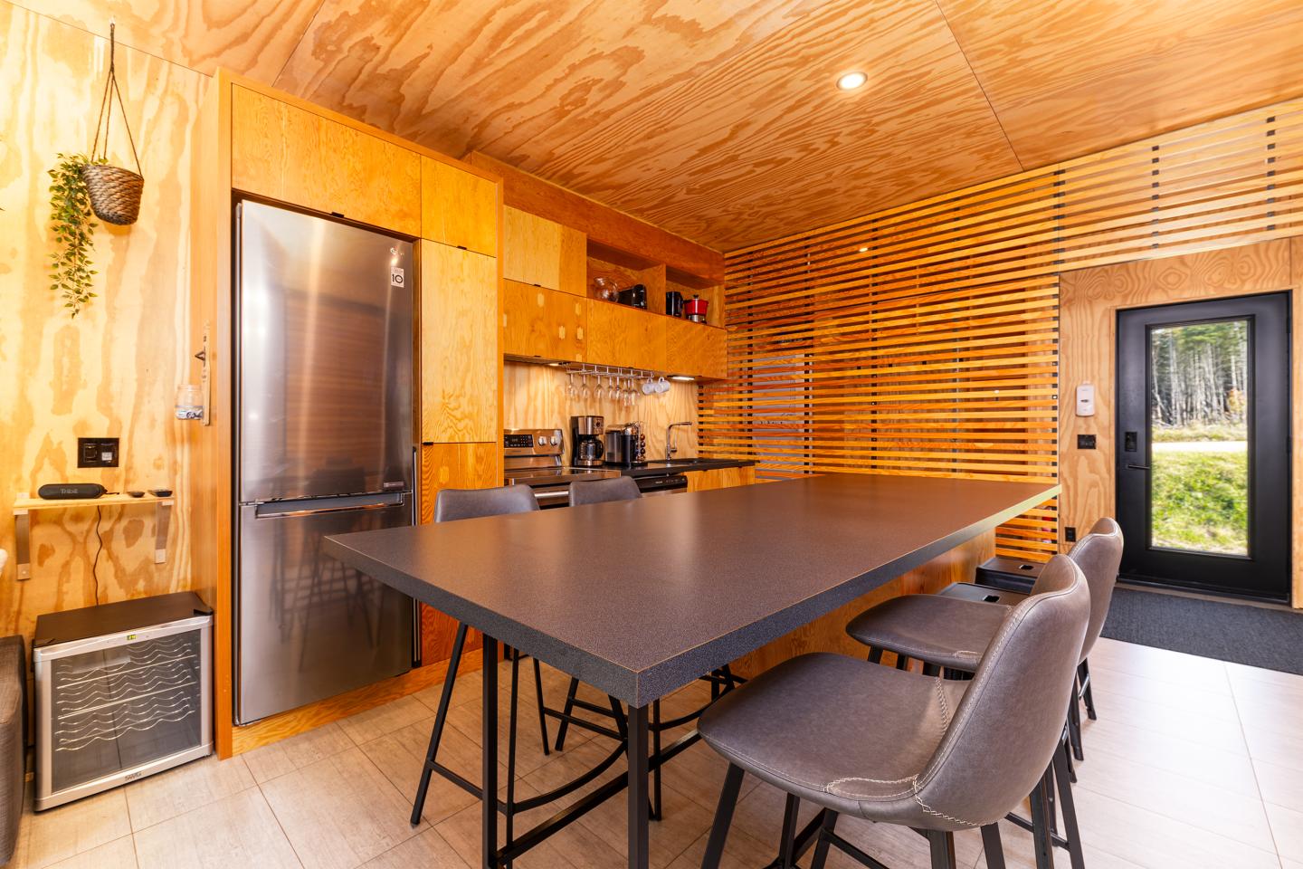 Cuisine moderne en bois avec îlot central noir et chaises grises.