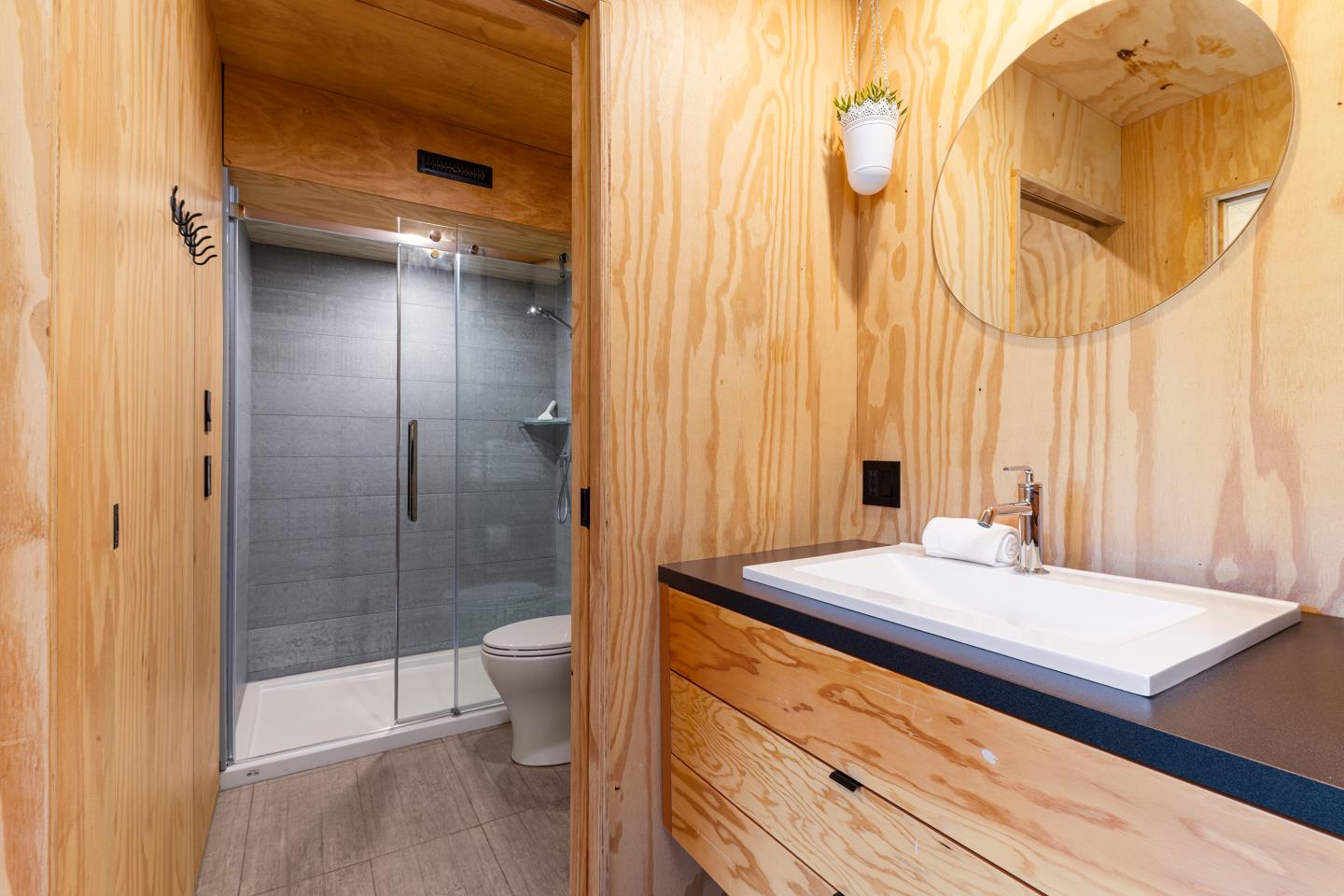 Salle de bain moderne en bois avec douche vitrée et lavabo.