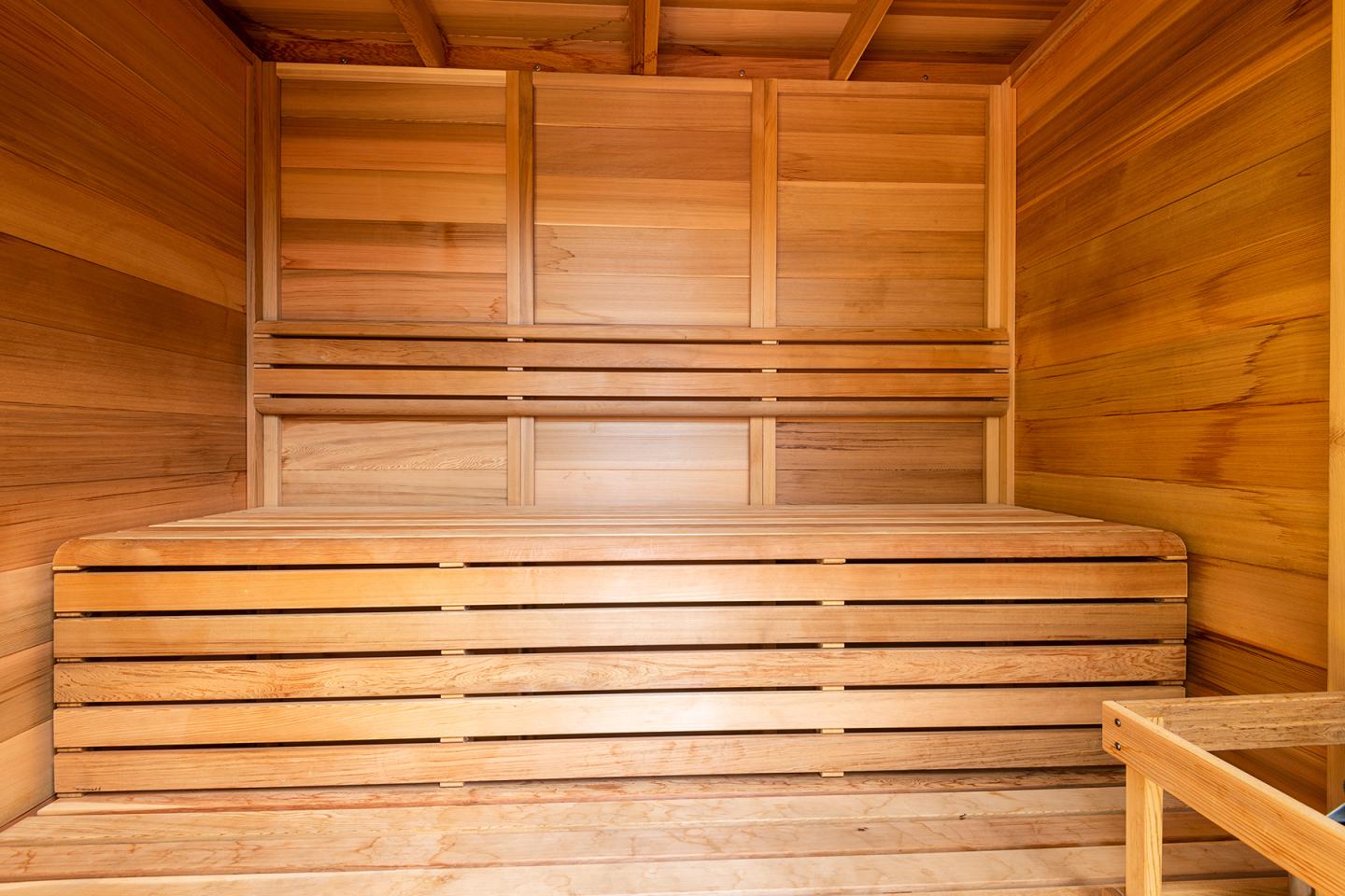 Sauna en bois clair avec banc et parois lambrissées.