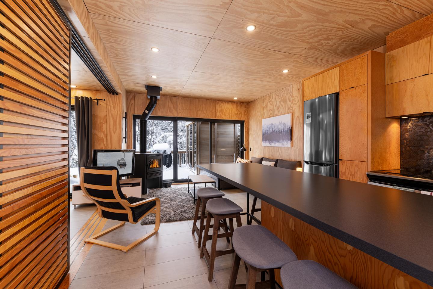 Intérieur moderne en bois, cuisine ouverte avec un grand bar et poêle à bois.