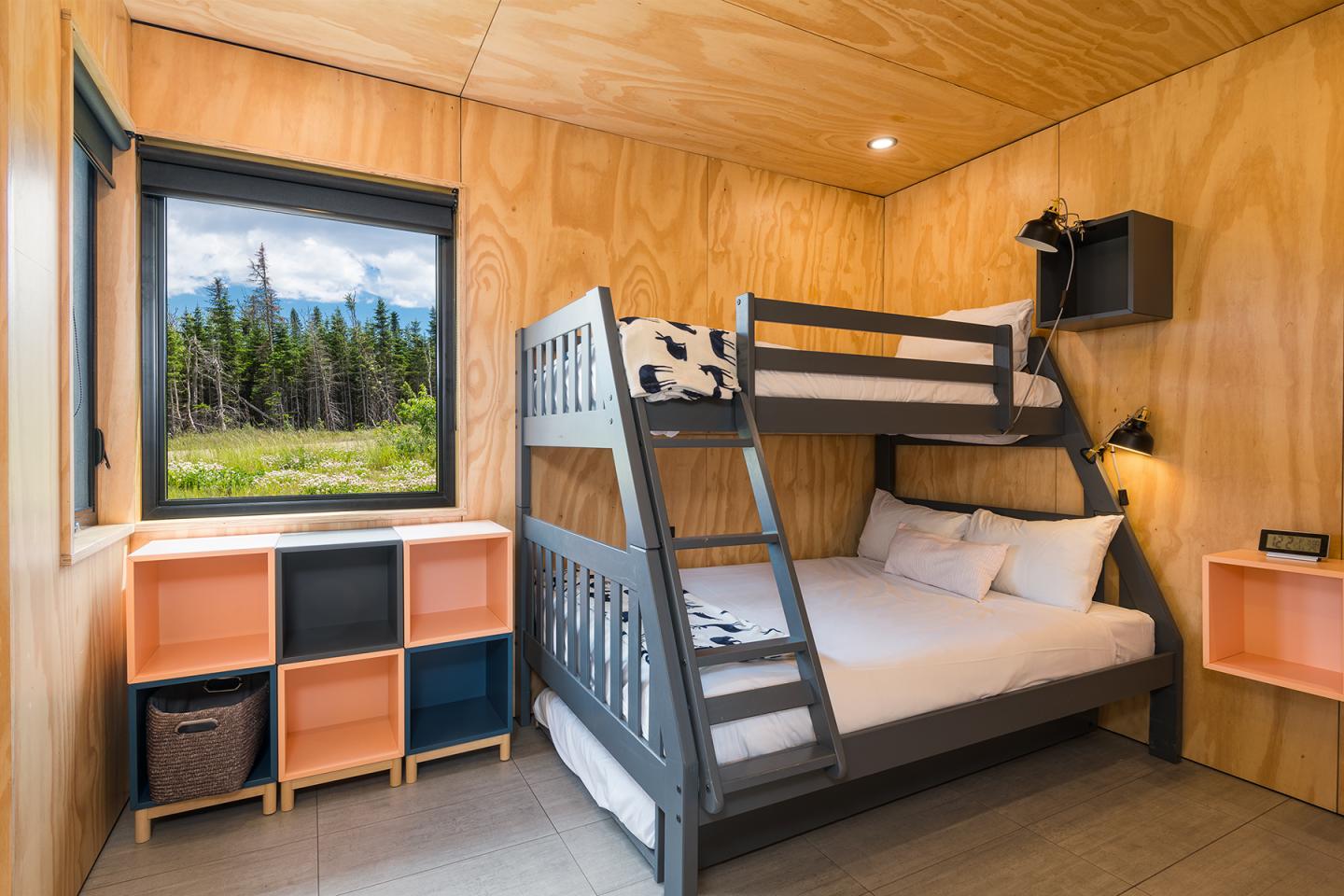 Lit superposé moderne, chambre en bois clair, vue forêt par fenêtre.