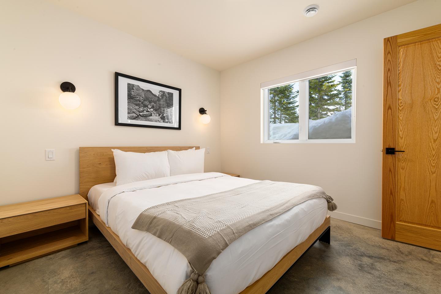 Chambre moderne avec lit double, lampe murale et fenêtre éclairée.
