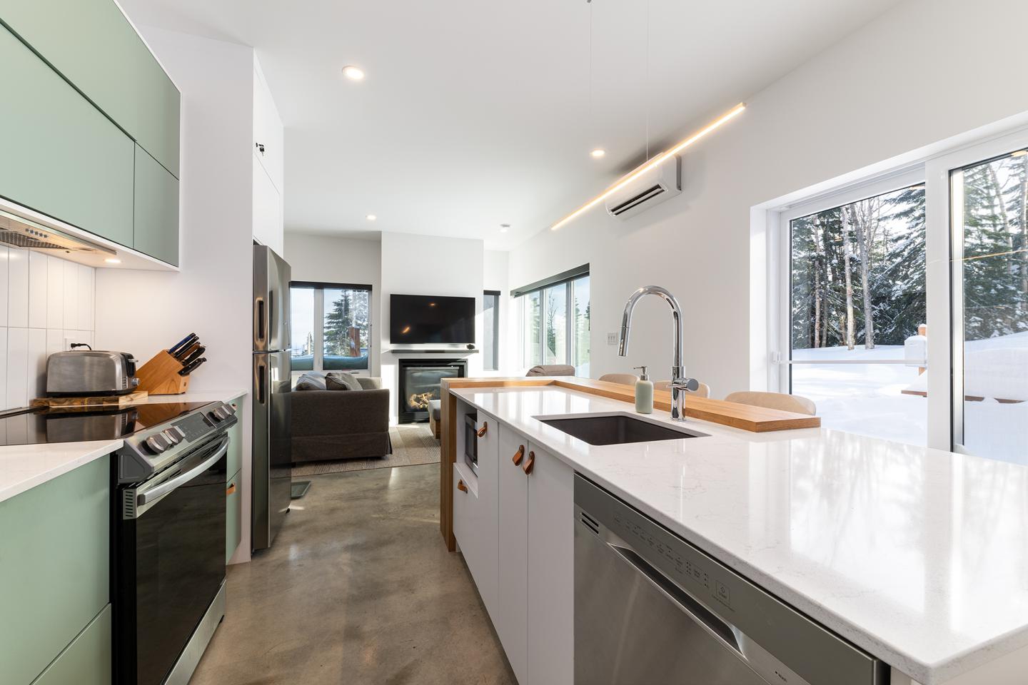Cuisine moderne avec plan de travail blanc, appareils inoxydables et vue sur la neige.