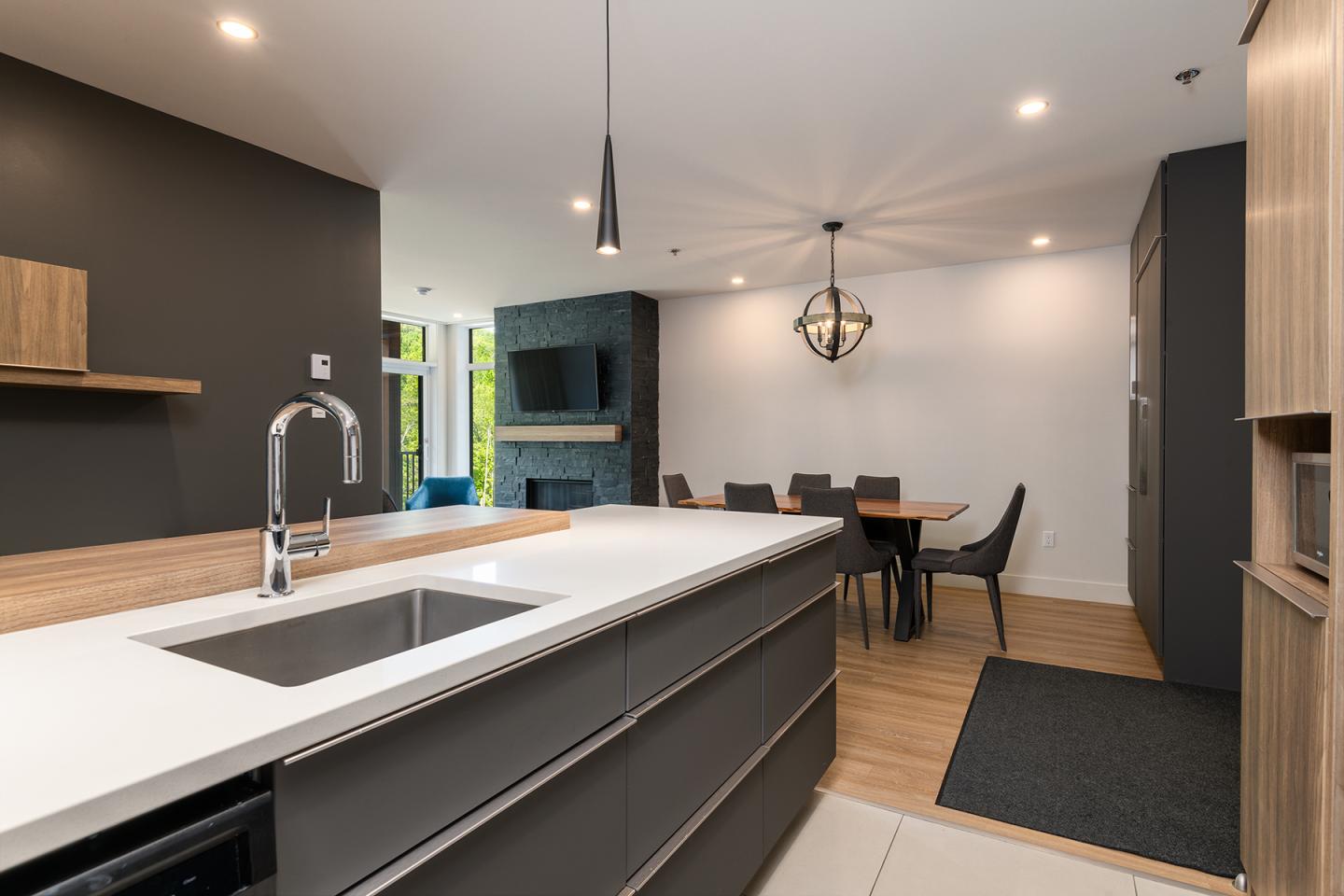 Cuisine moderne avec un îlot, table à manger et éclairage suspendu.
