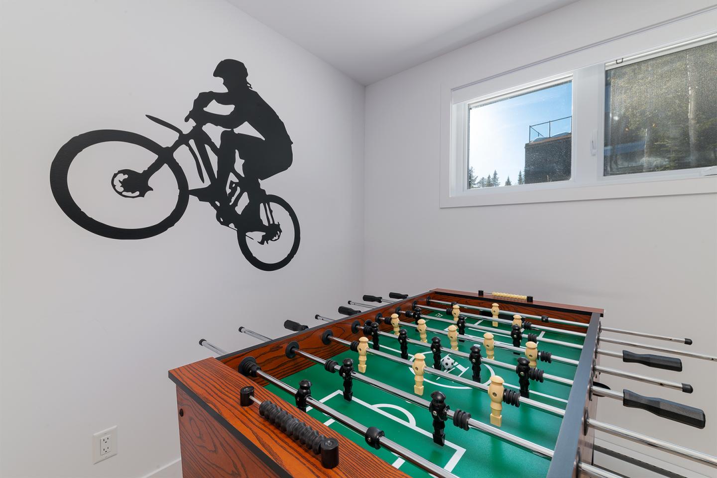 Baby-foot devant un mur décoré d'une silhouette de cycliste.