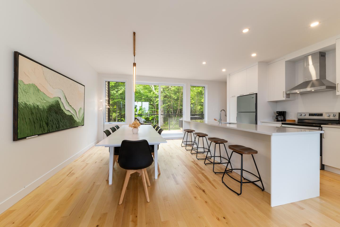 Cuisine moderne lumineuse avec îlot central, tabourets et grande table à manger.