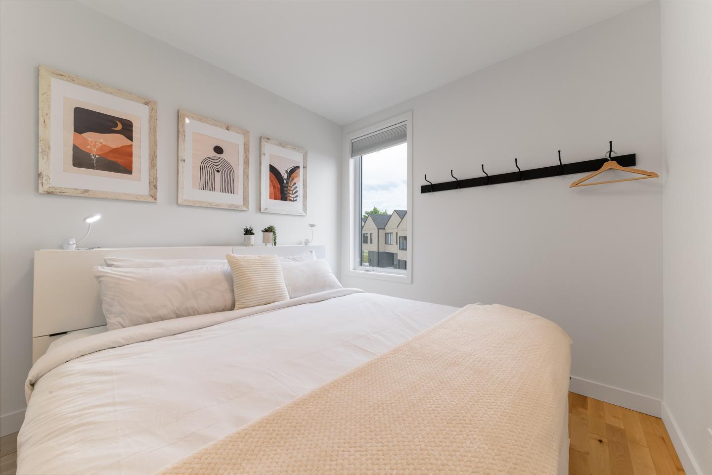 Chambre lumineuse avec lit double, tableaux et fenêtre.