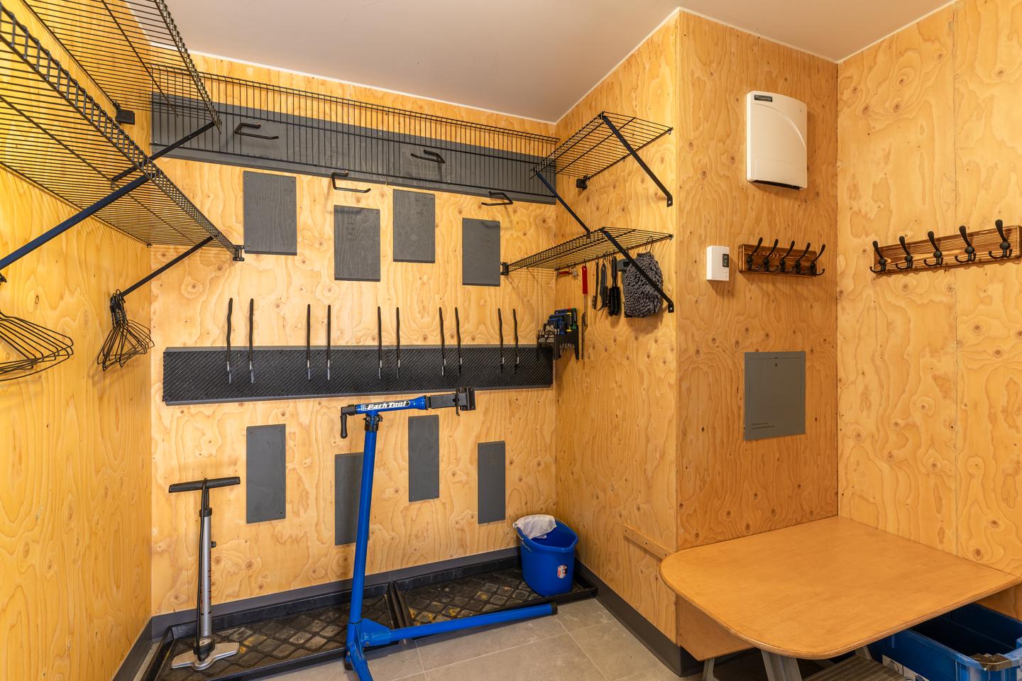 Salle de rangement avec supports muraux et table en bois.