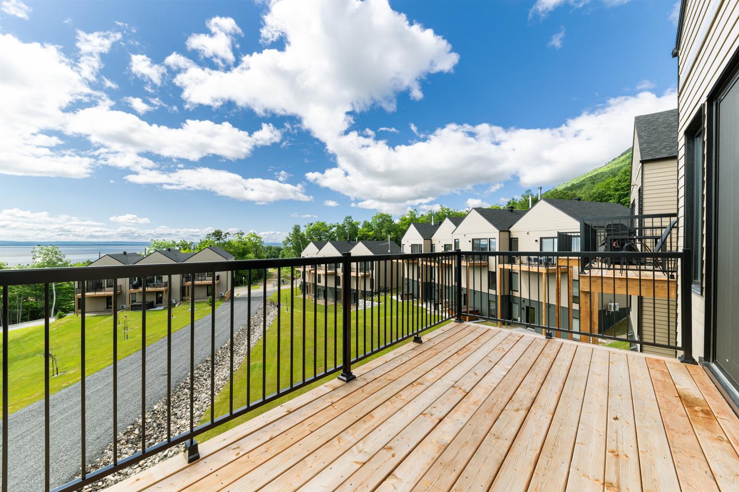 Terrasse en bois avec vue sur maisons modernes et ciel bleu.