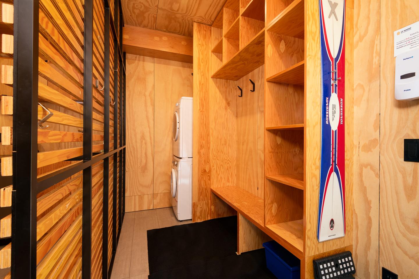 Petite entrée en bois avec étagères ouvertes, deux crochets et une décoration murale.