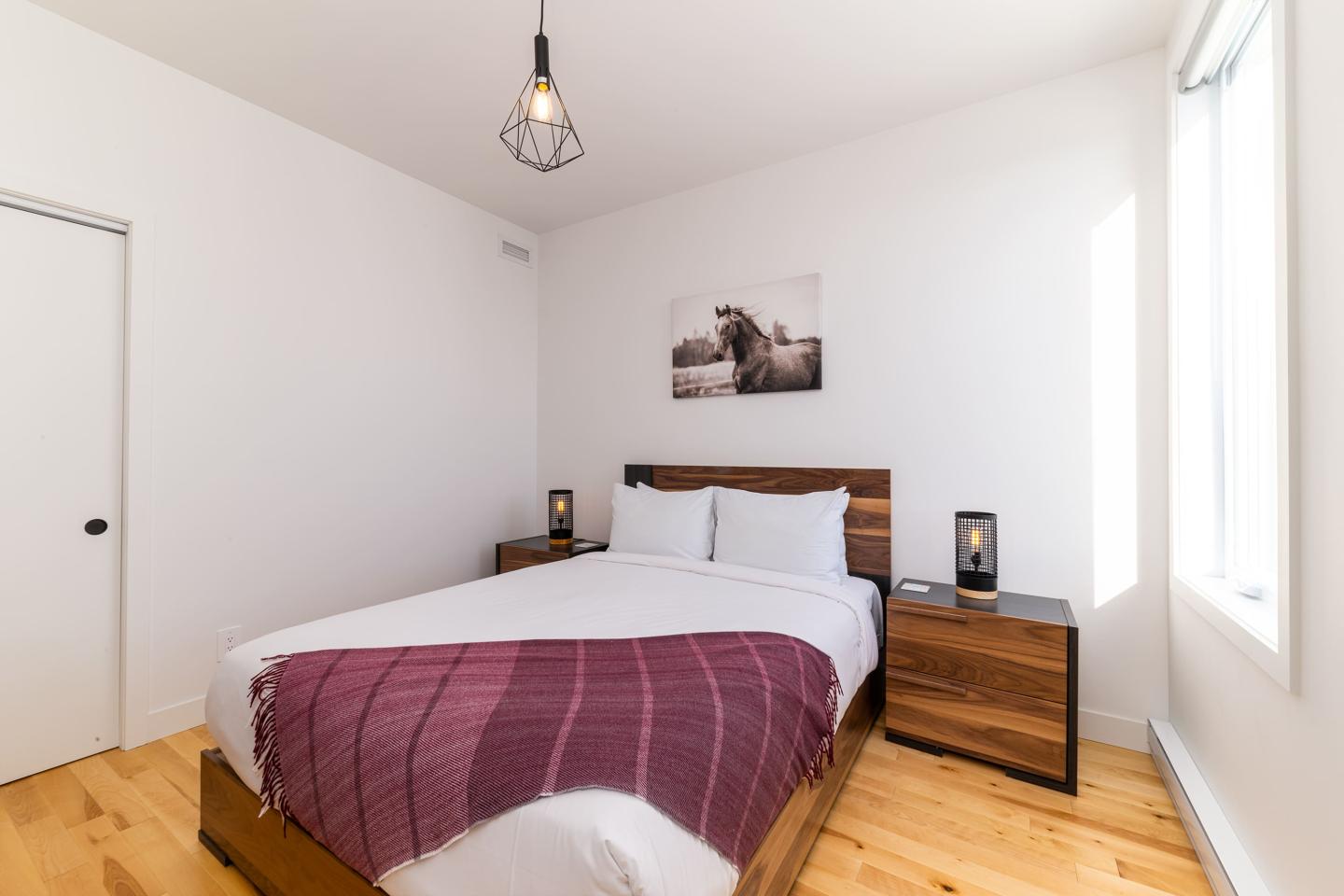 Chambre moderne avec lit double, table de chevet et luminaire suspendu.