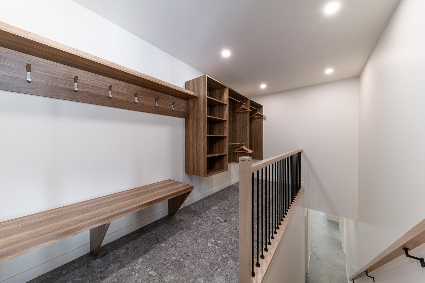 Vestiaire moderne avec bancs en bois et étagères adjacentes.