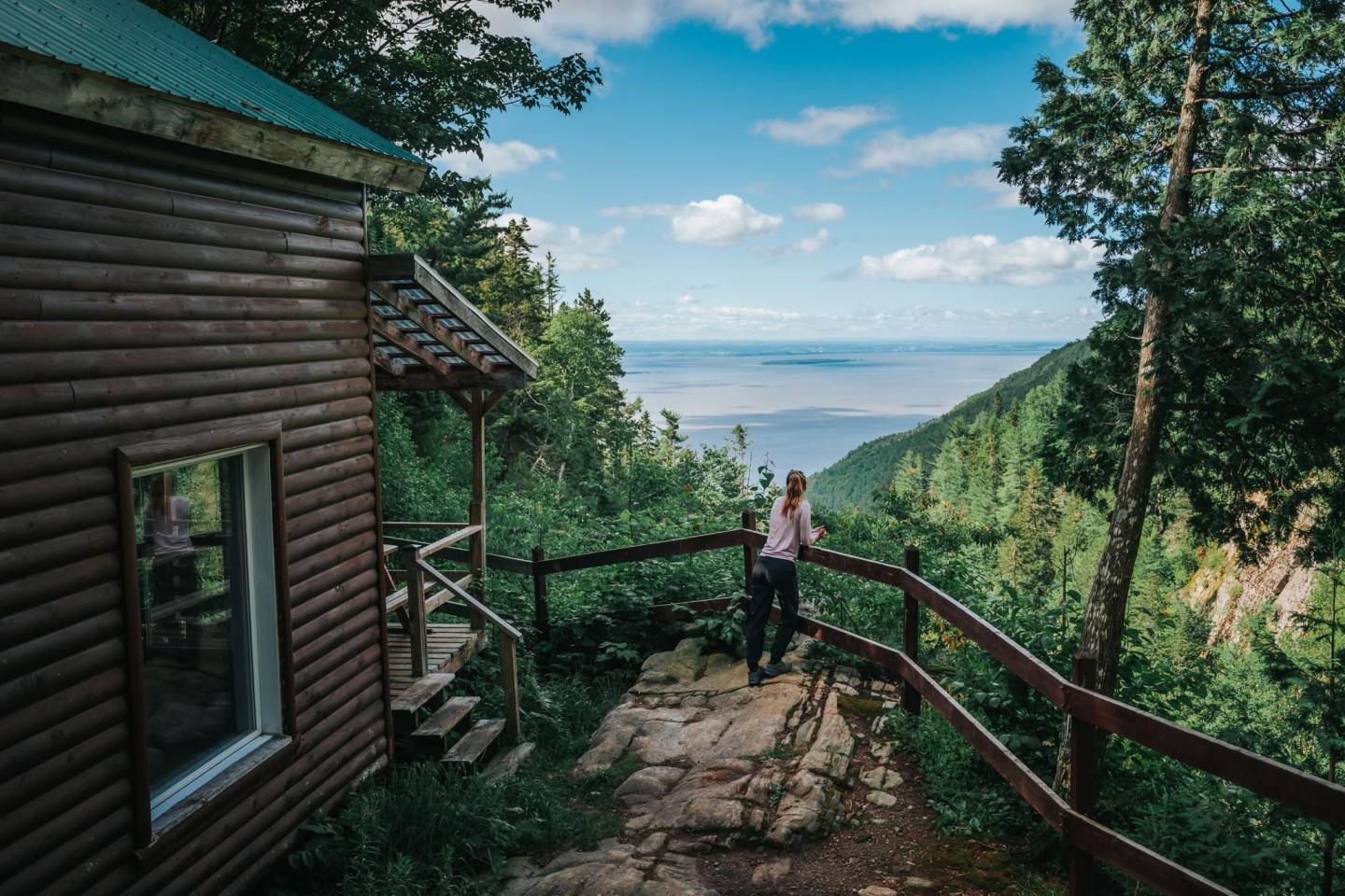 Un chalet en bois près d'un belvédère surplombant une vallée verdoyante.