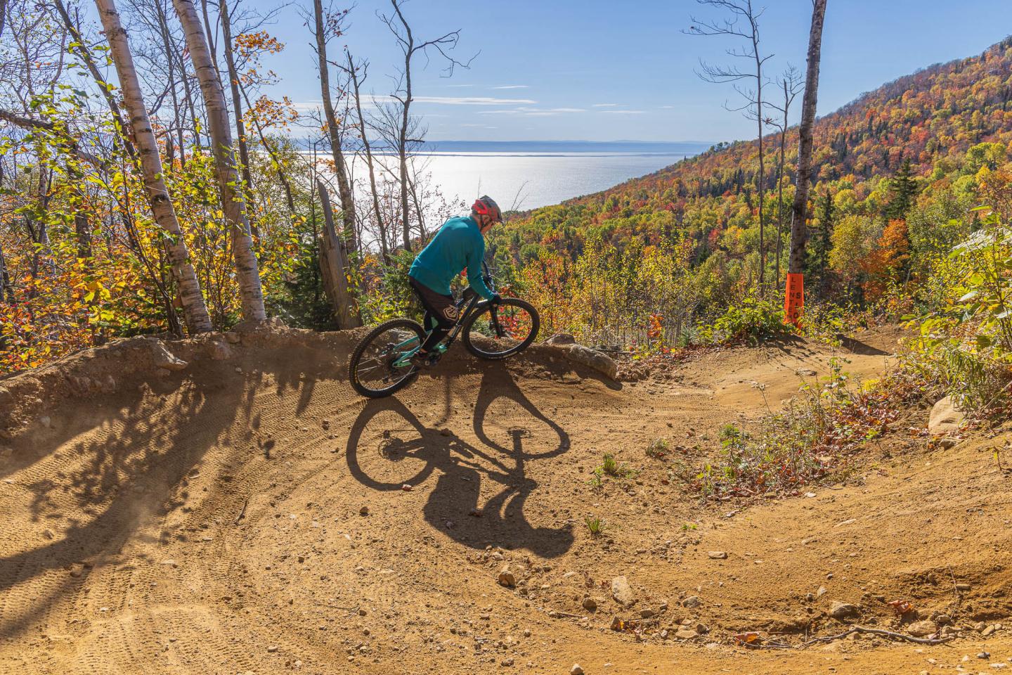 Cycliste sur un sentier de montagne en automne, près d'un lac.