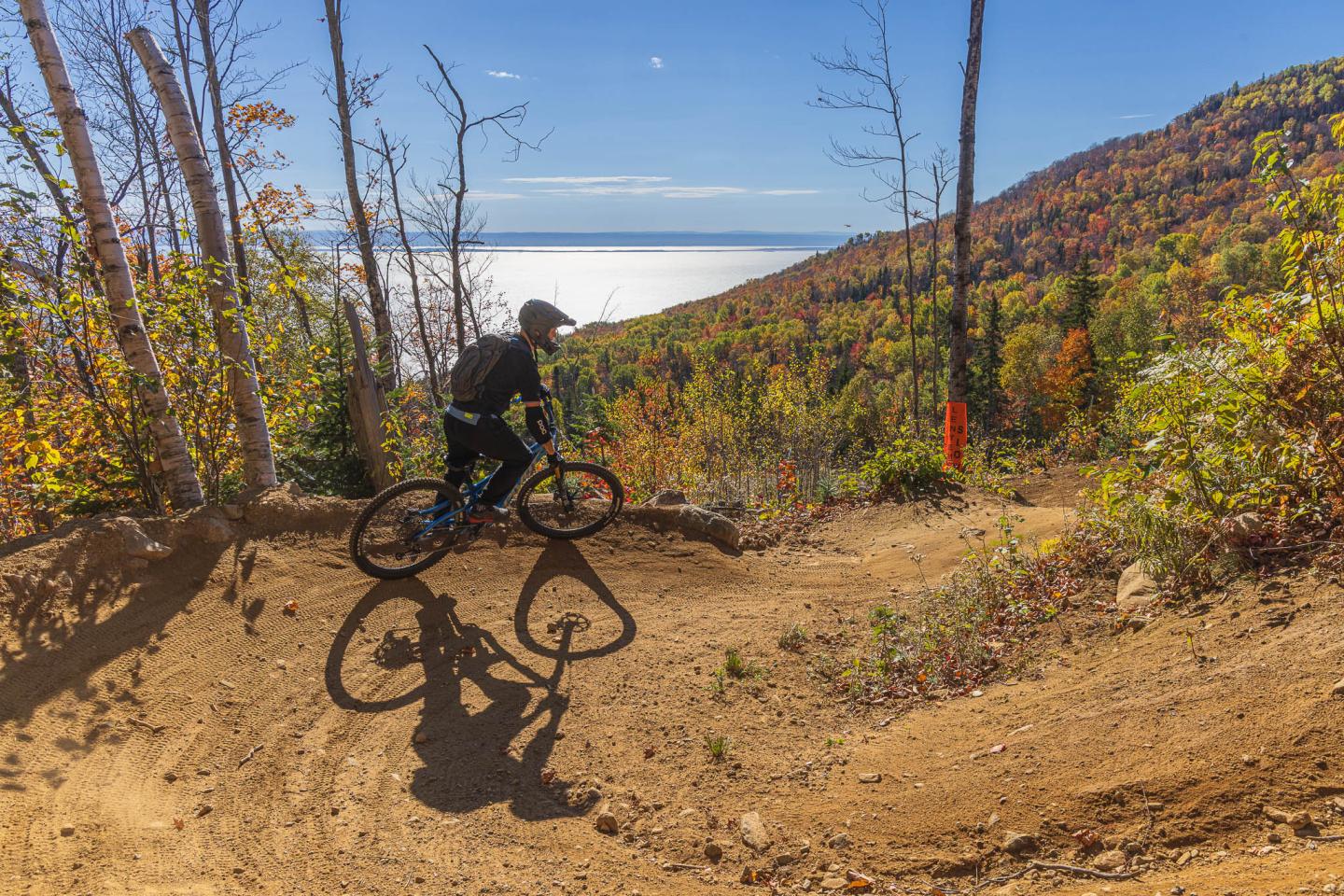 Cycliste en VTT sur un sentier de montagne en automne, vue sur mer.