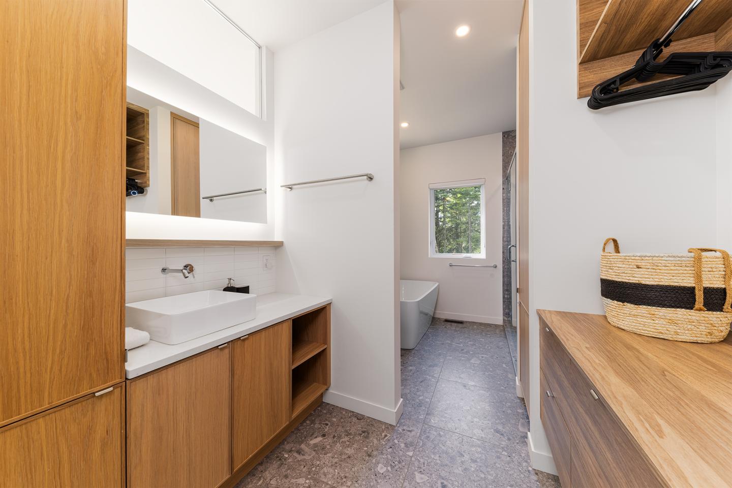 Salle de bain moderne avec lavabo, baignoire et meuble en bois clair.