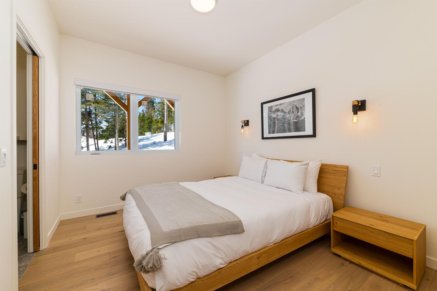 Chambre lumineuse avec lit double, vue sur la neige, mur blanc.