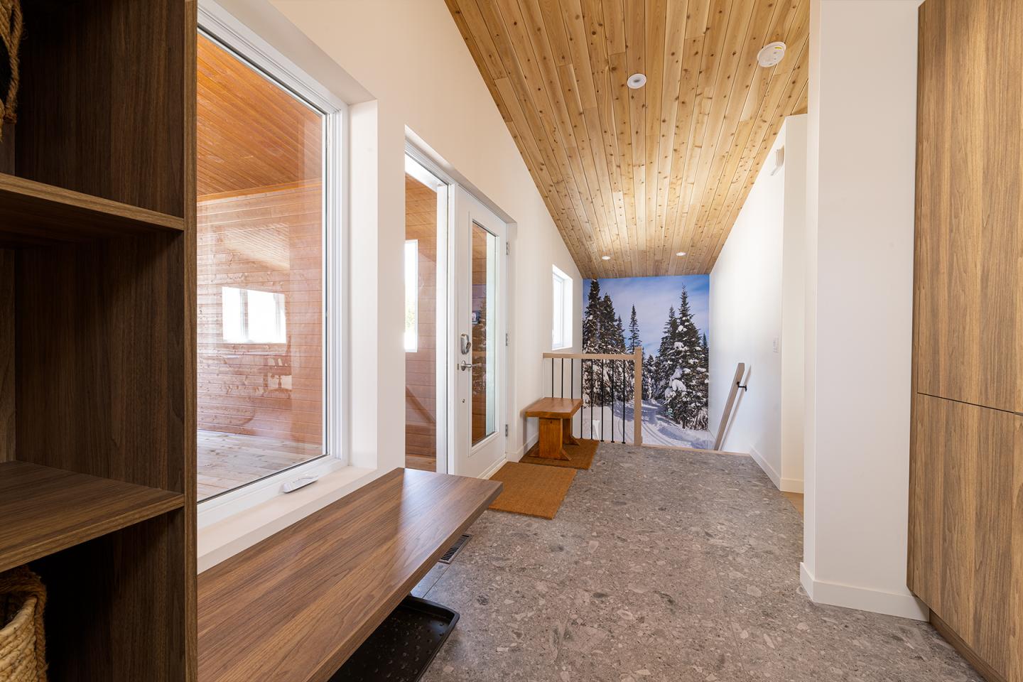 Couloir lumineux en bois avec vue sur un paysage enneigé.
