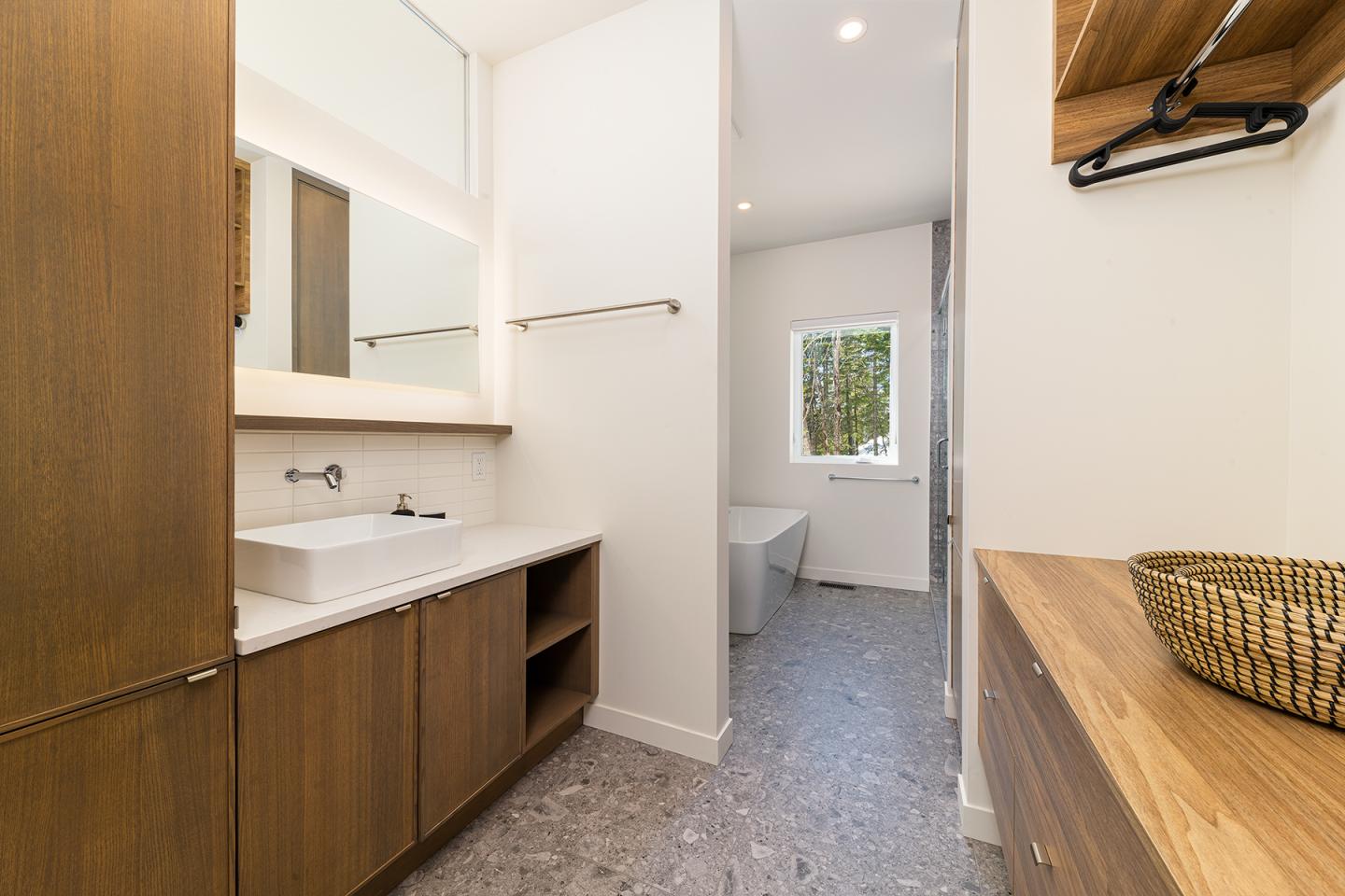 Salle de bain moderne avec lavabo en bois, baignoire, et fenêtre.