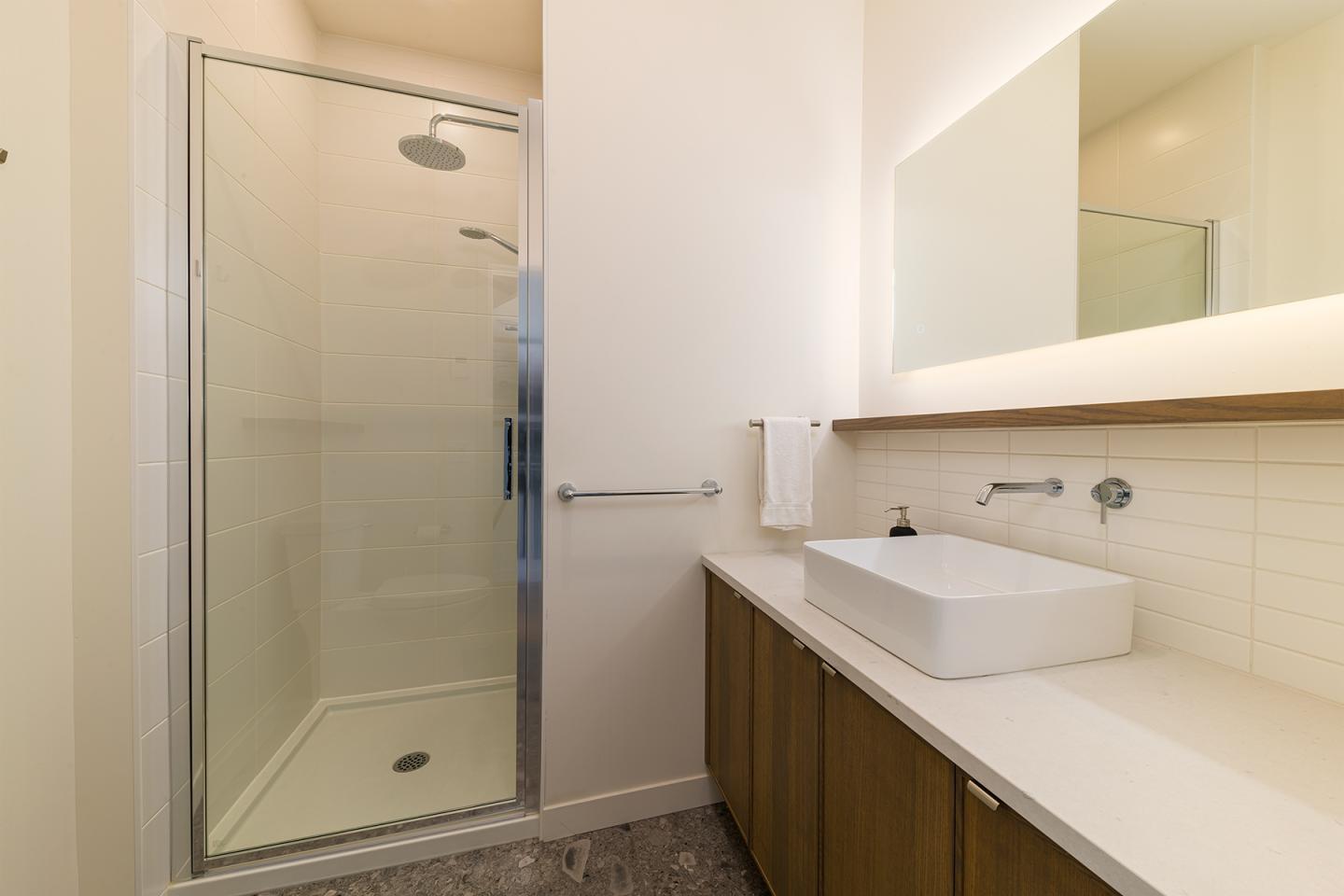 Salle de bain moderne avec douche vitrée, lavabo et miroir.