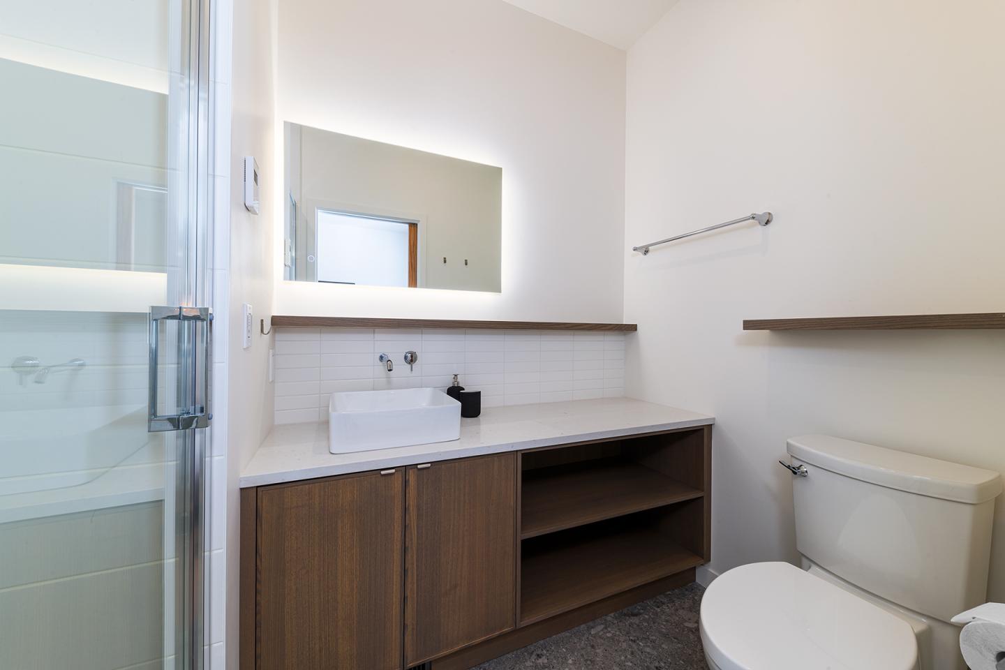 Salle de bain moderne avec lavabo, miroir éclairé et toilettes.