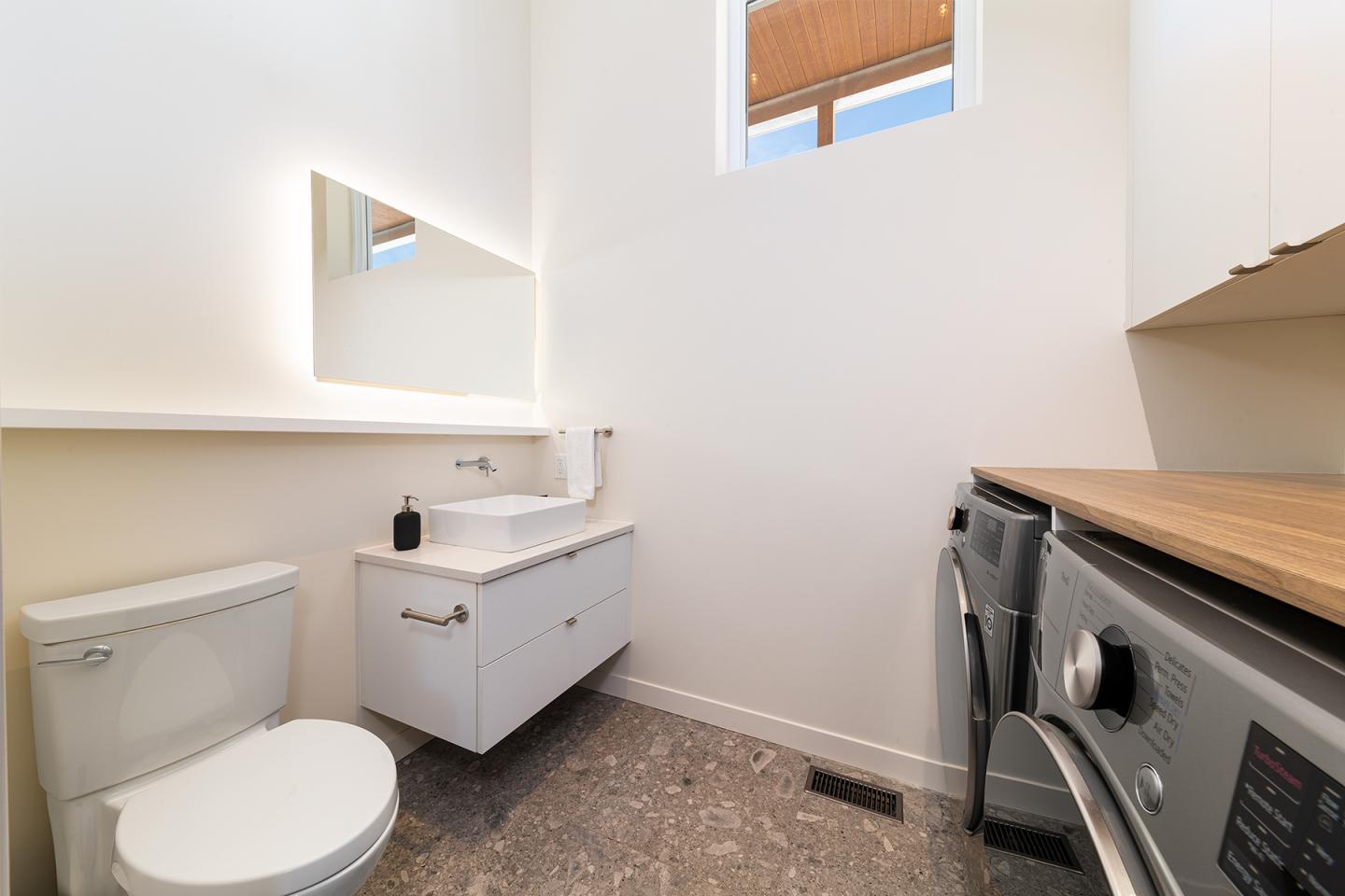 Salle de bain moderne avec lavabo, toilettes et machine à laver.