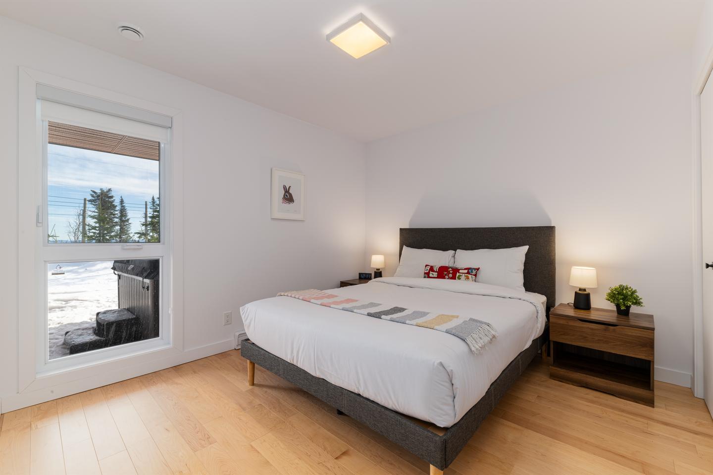 Chambre moderne avec lit double, lampes de chevet, sol en bois.