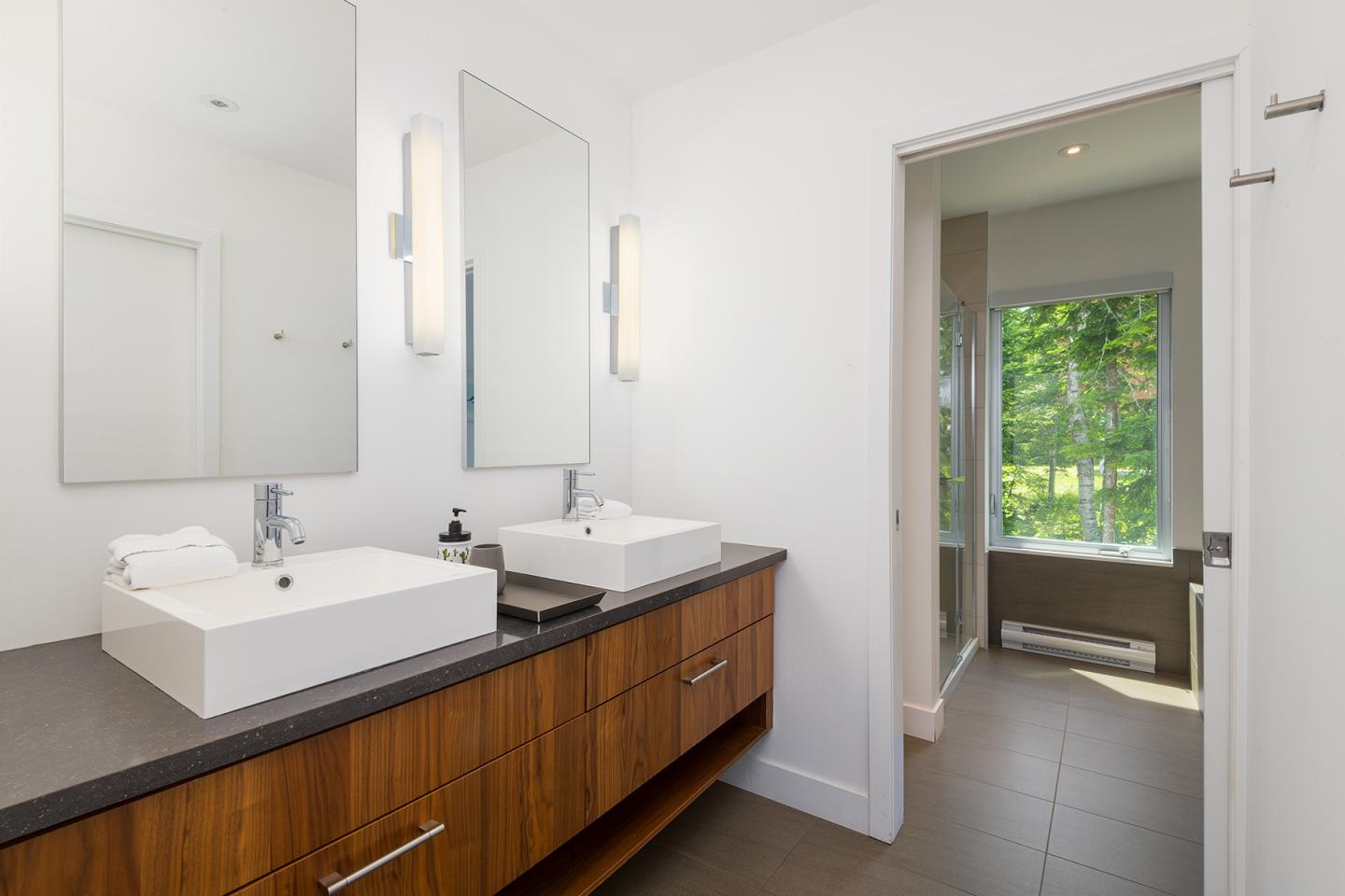 Salle de bain moderne avec deux lavabos, éclairage naturel par une grande fenêtre.