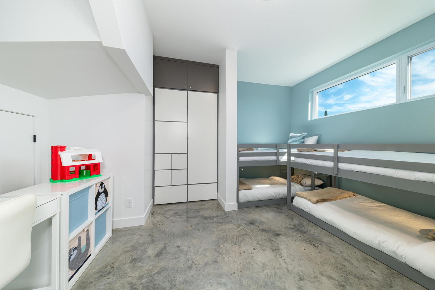 Chambre d'enfants avec lits superposés, mur bleu et jouets colorés.