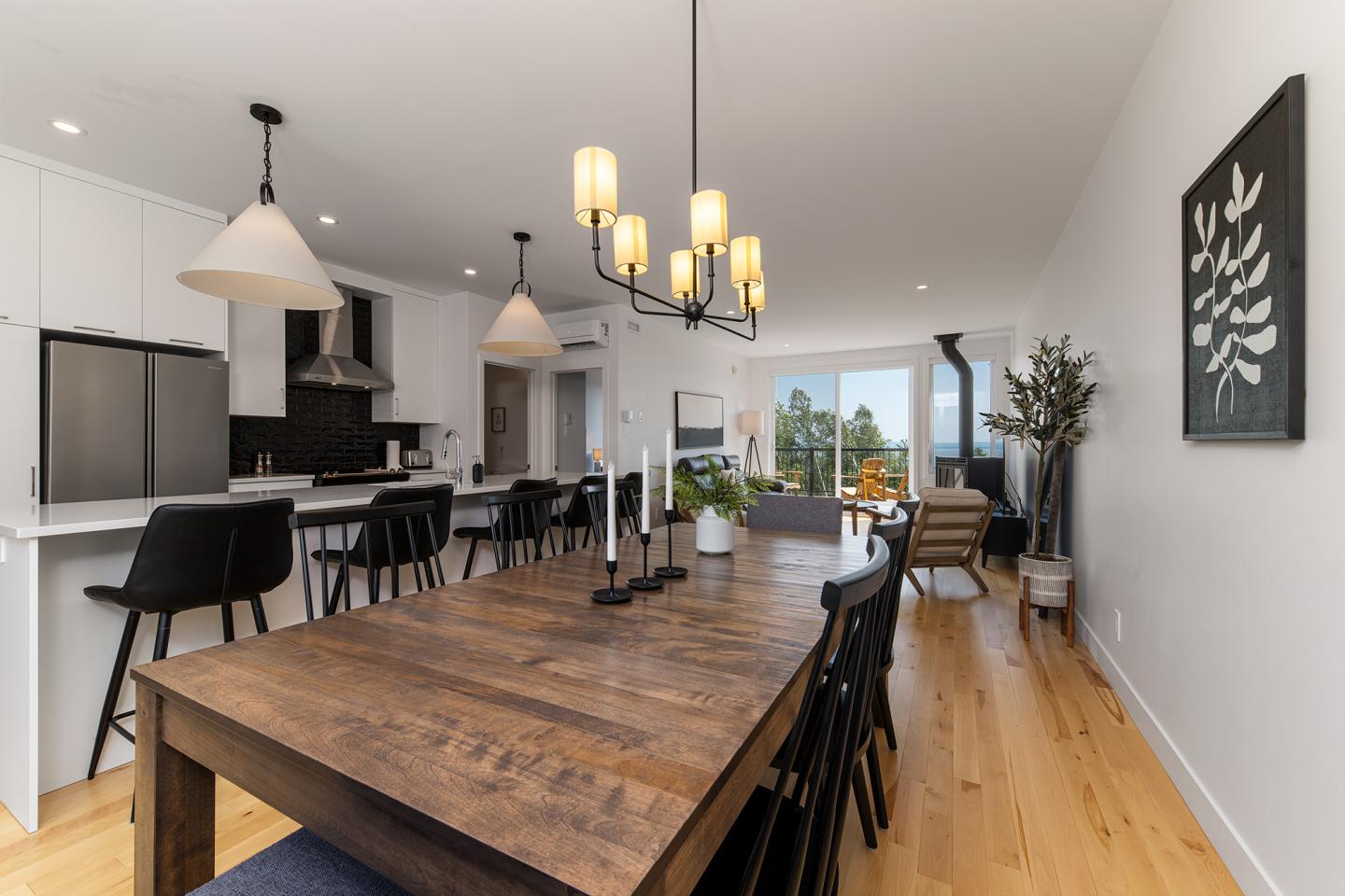 Salle à manger moderne avec table en bois, chaises noires et luminaires élégants.