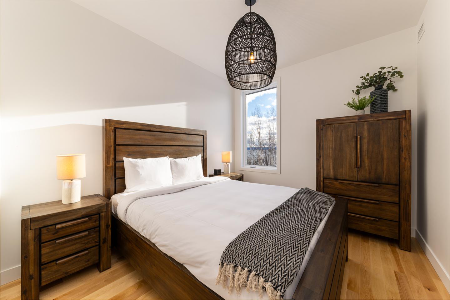 Chambre moderne avec lit double, meubles en bois et lumière naturelle.