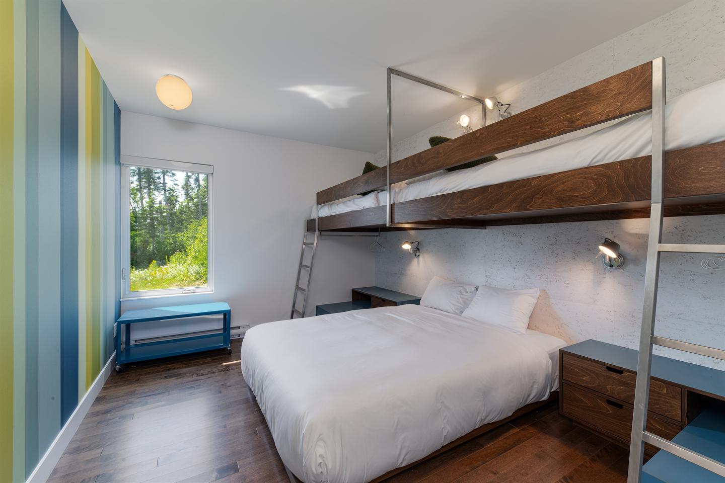 Chambre moderne avec lit superposé, mur coloré et fenêtre donnant sur la verdure.