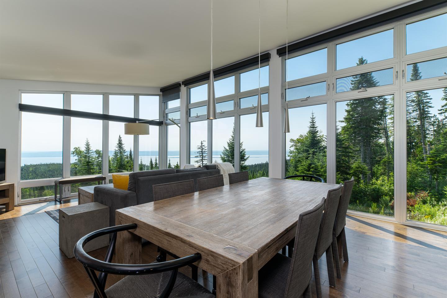 Salon moderne avec vue sur la mer, grandes fenêtres et mobilier contemporain.