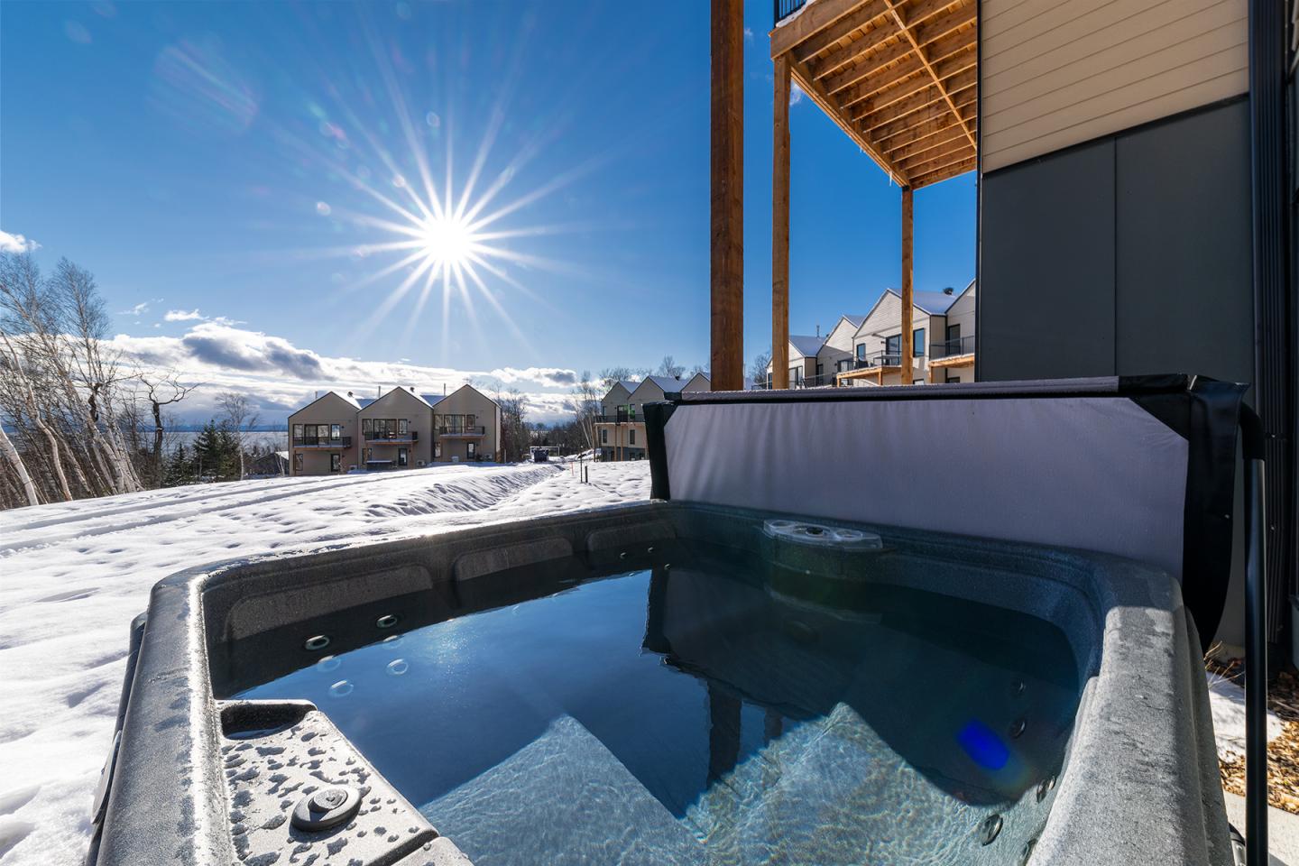 Spa extérieur avec vue sur montagne enneigée par temps ensoleillé.