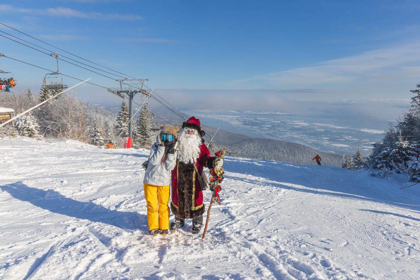 Deux enfants en tenue d’hiver avec des skis sur une piste enneigée.