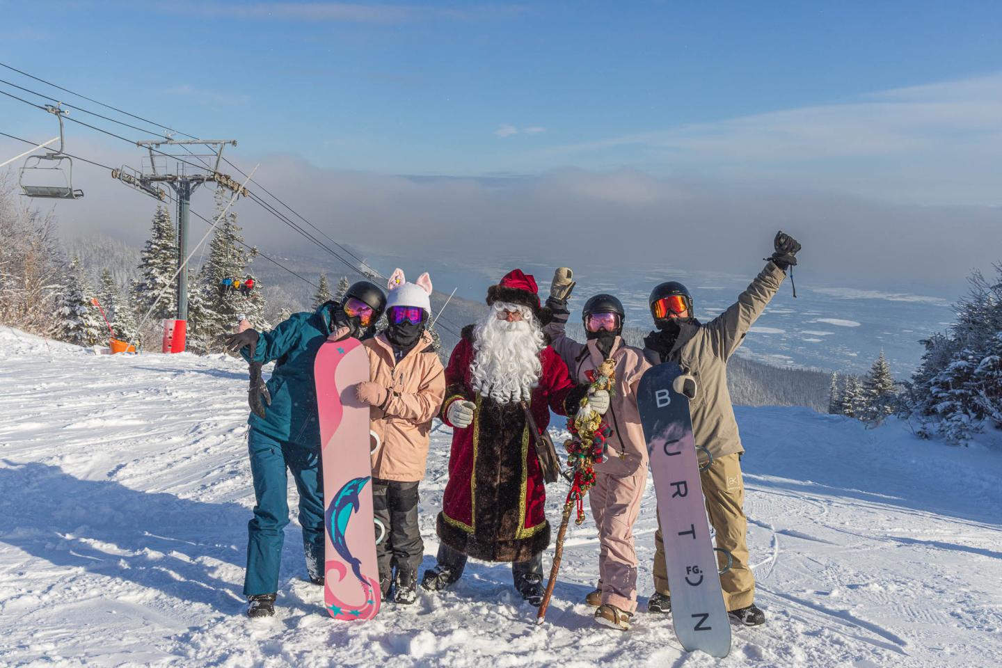 Quatre skieurs souriants posent sur une piste enneigée avec vue sur les montagnes.