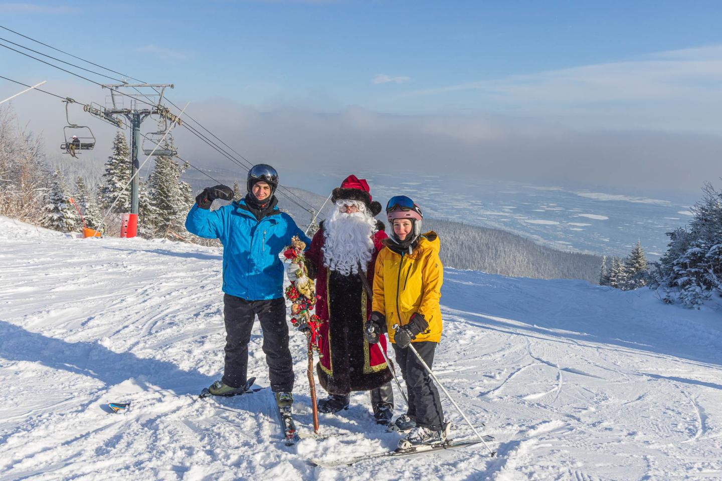 Trois skieurs souriants sur une piste enneigée, avec vue sur la vallée.