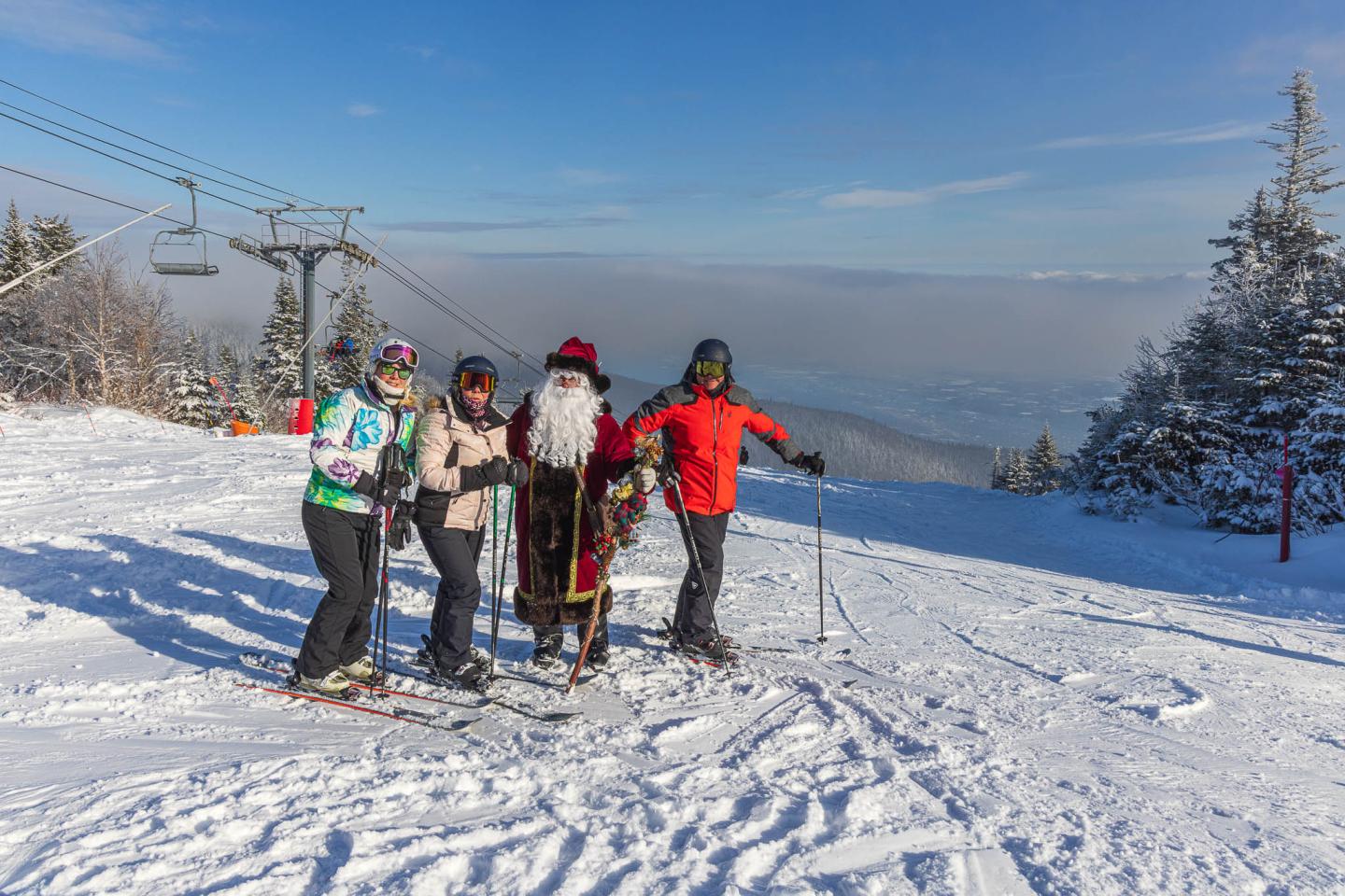 Quatre skieurs posent sur une piste enneigée sous un ciel bleu.