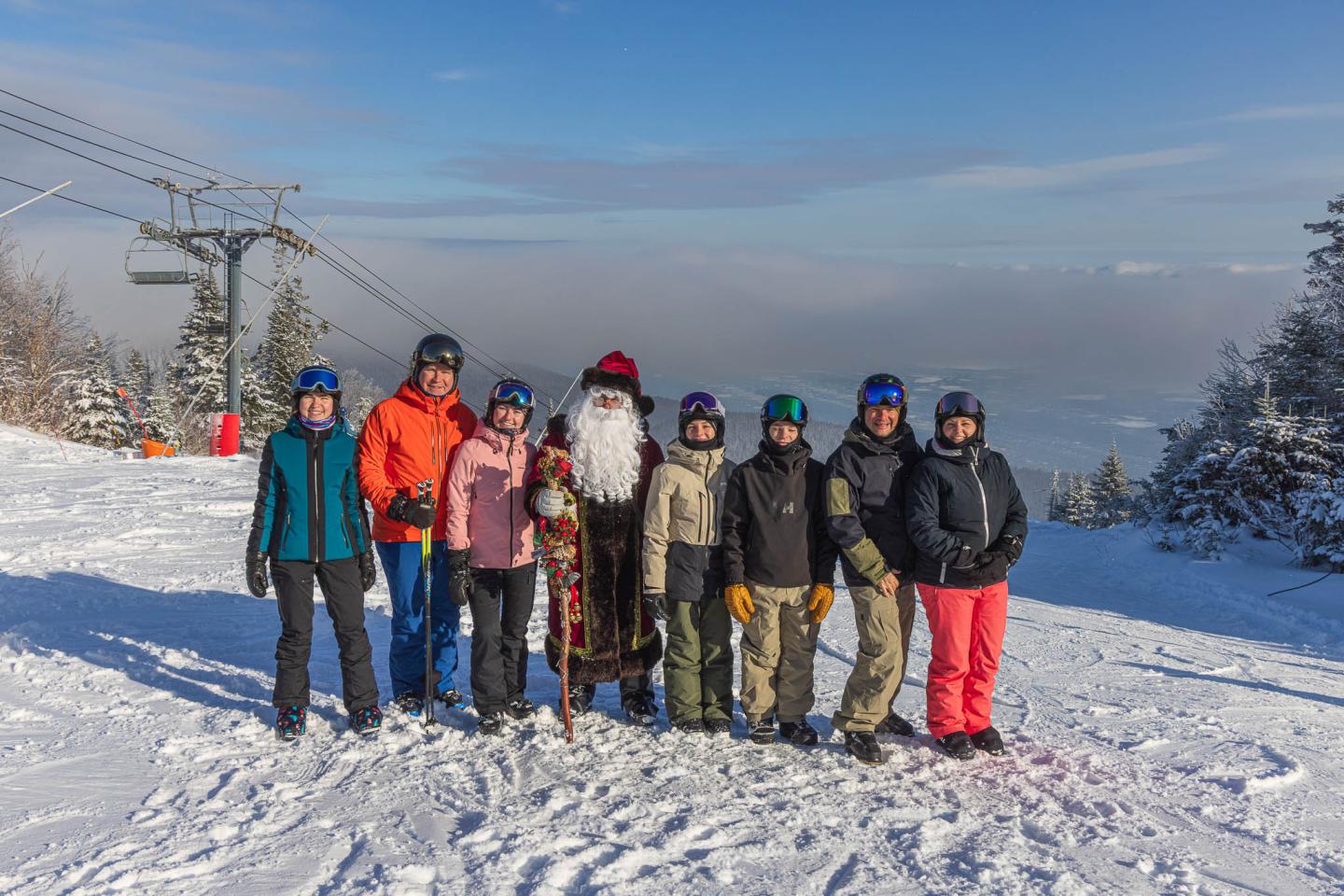Groupe de neuf personnes en tenue de ski sur une piste enneigée.