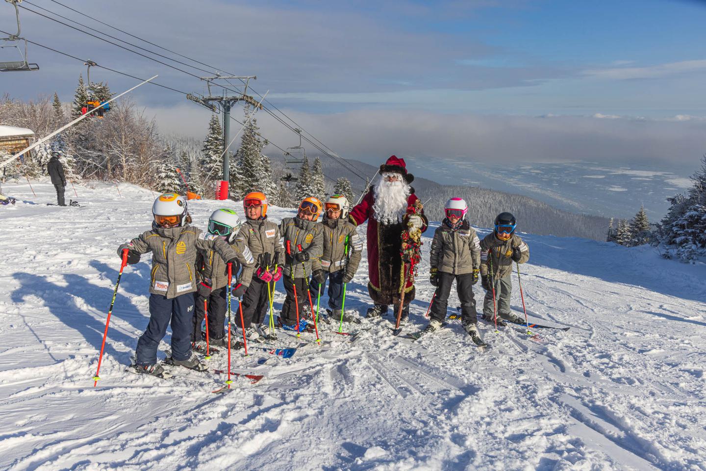Groupe de skieurs en tenue colorée sur une piste enneigée, montagnes au loin.