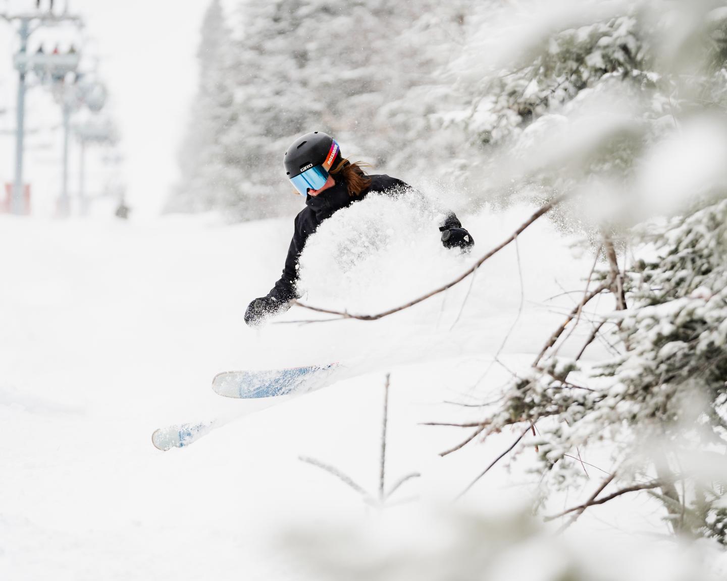 Snowboardeur en plein saut dans une forêt enneigée.