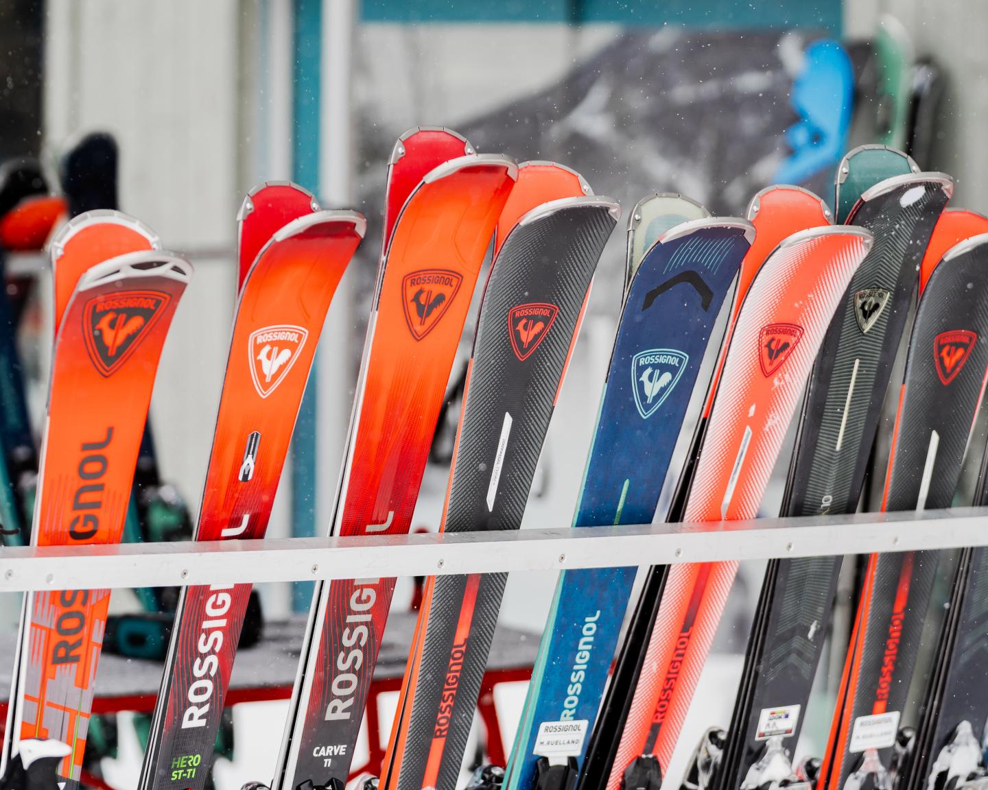 Rangée de skis orange, rouges et noirs dans un magasin.
