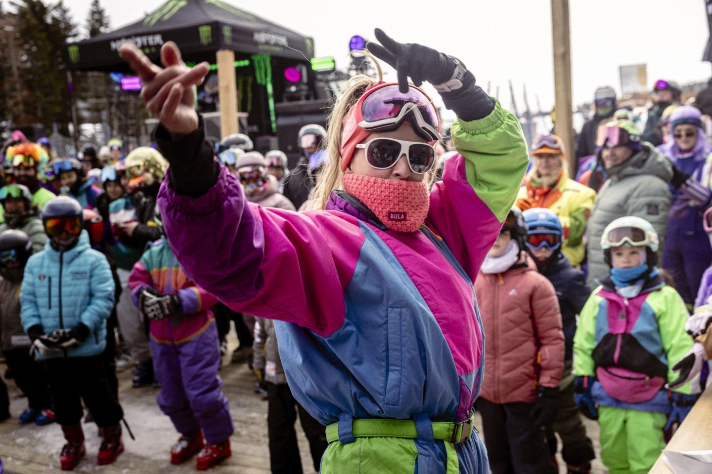 Manifestante masquée en rose et bleu levant le poing lors d’un rassemblement hivernal.
